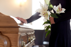 Woman with white lily flowers and coffin at funeral in church